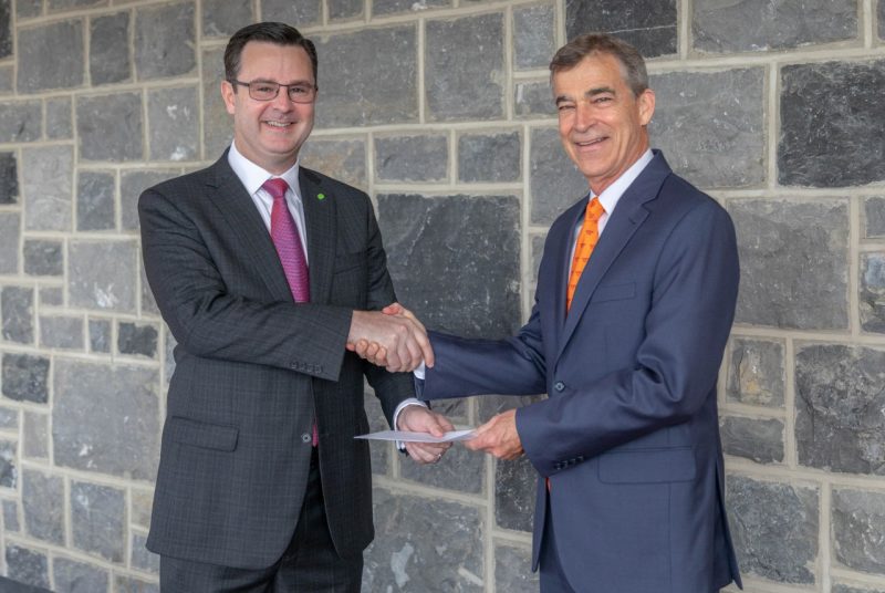Kevin Lane (left), a principal at Deloitte and Virginia Tech alumnus in accounting, hands over the Deloitte Foundation's matching gift agreement to and shakes hands with Charlie Phlegar, vice president for advancement at Virginia Tech.