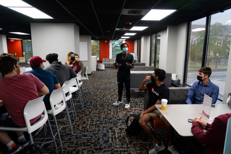 While gathered inside the new home for the Apex Center for Entrepreneurs, Virginia Tech student Tahjere Lewis talks with other students about his business venture, Aunt Carol's Sauce. 