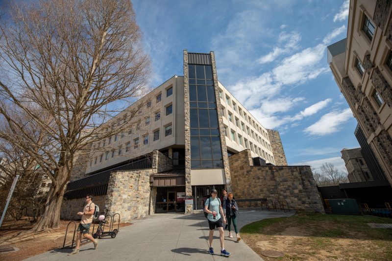 Grey Hokie Stone McBryde Hall on a sunny spring day with many young people exiting the building