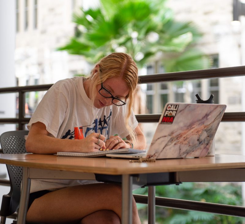 student with laptop and paper in Pamplin Hall 