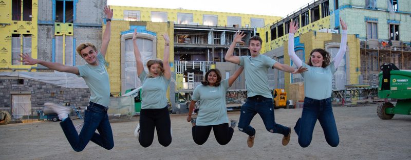 PRISM students jump for joy in front of the Data and Decision Sciences construction site.
