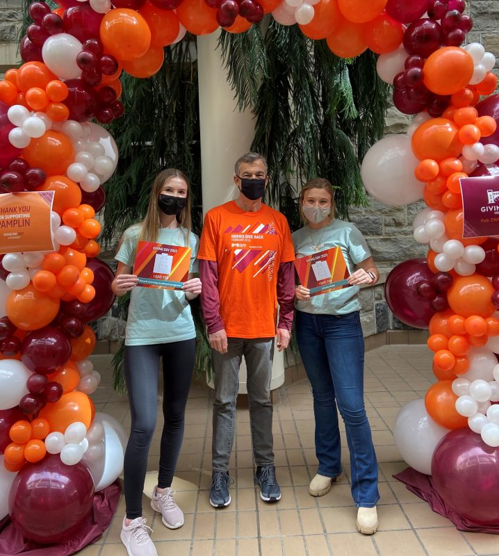Vice President for the division of Advancement, Charles D. Phlegar, with PRISM students Emily Bookstaver (left) and Kathleen Finn (right) at Pamplin's Giving Day HQ, aka the Pamplin atrium, during Giving Day 2022.