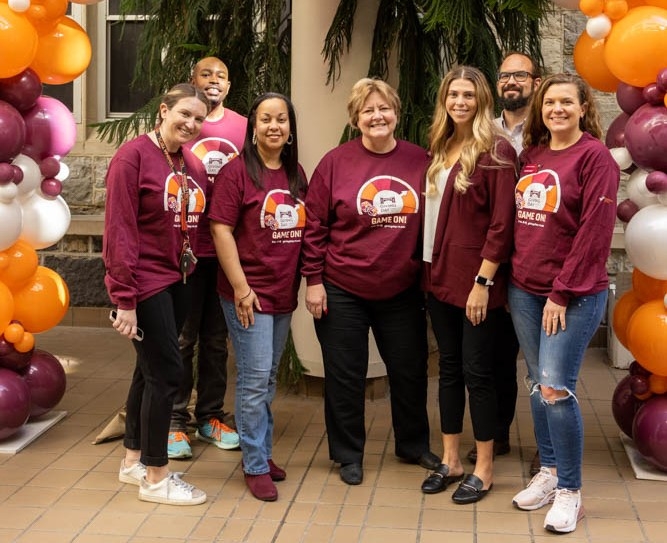 Pamplin faculty pose with Interim Dean Russell under the Giving Day balloon arch